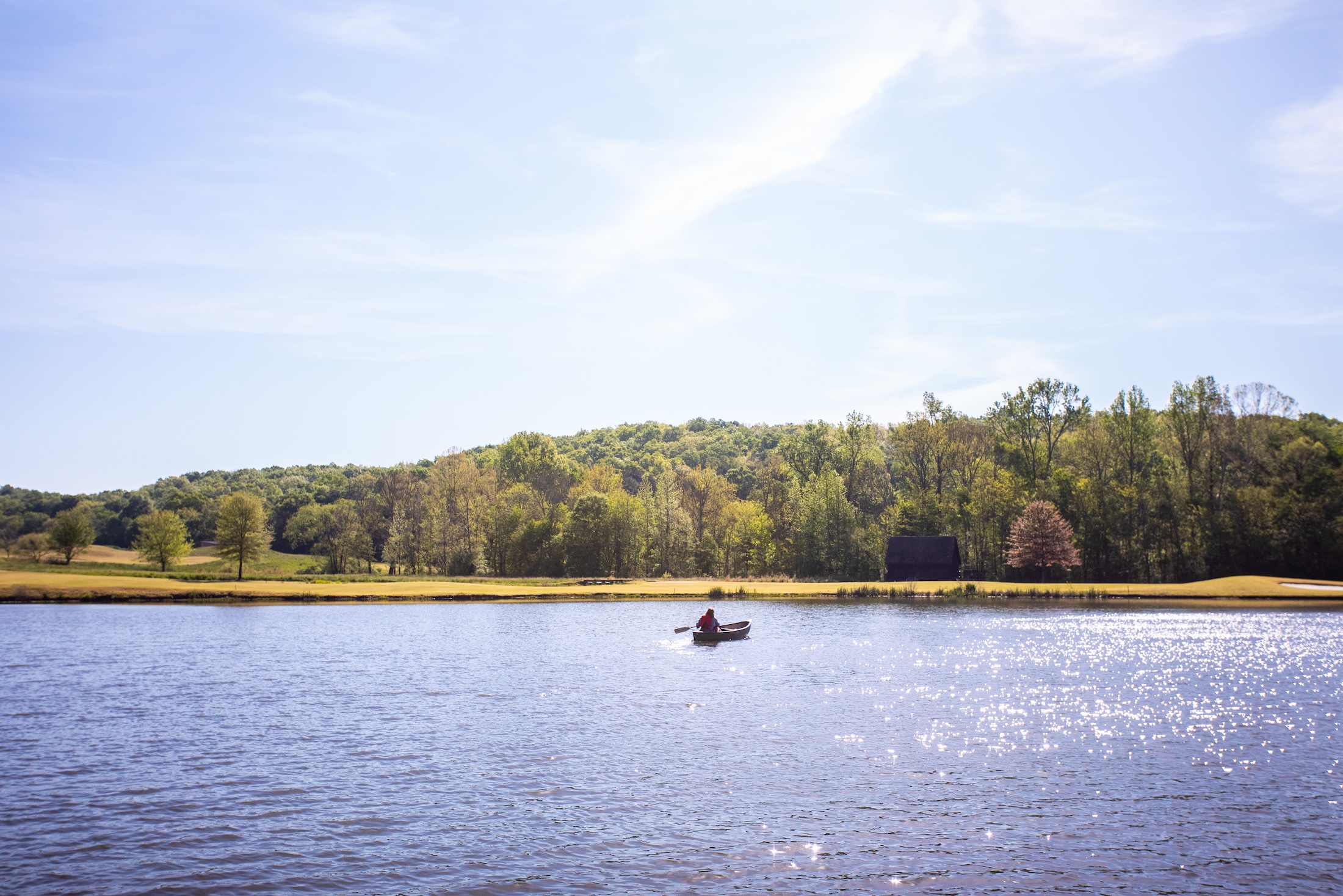 A person canoeing on a lake on a sunny day at Barnsley Resort.