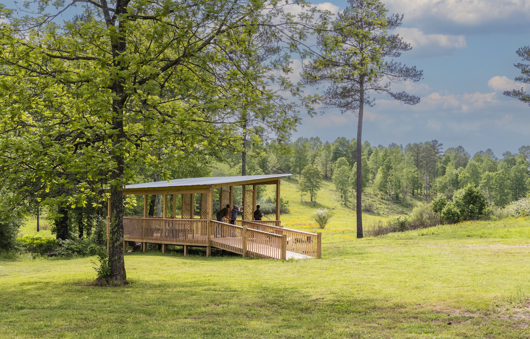 A man is shooting a gun while two others watch at Beretta Shooting Grounds five stand at Barnsley Resort.