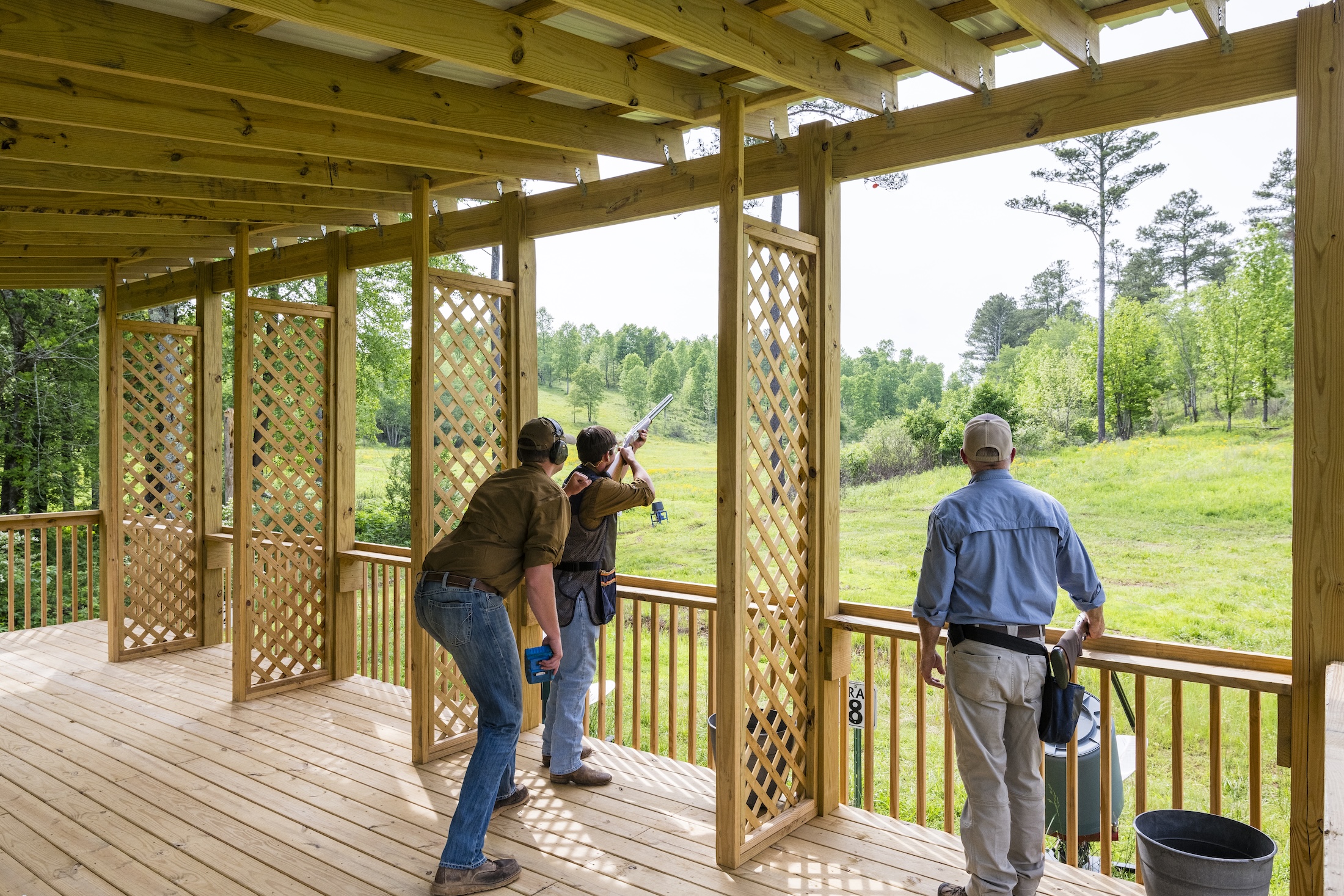 A man is shooting a gun while two others watch at Beretta Shooting Grounds five stand at Barnsley Resort.