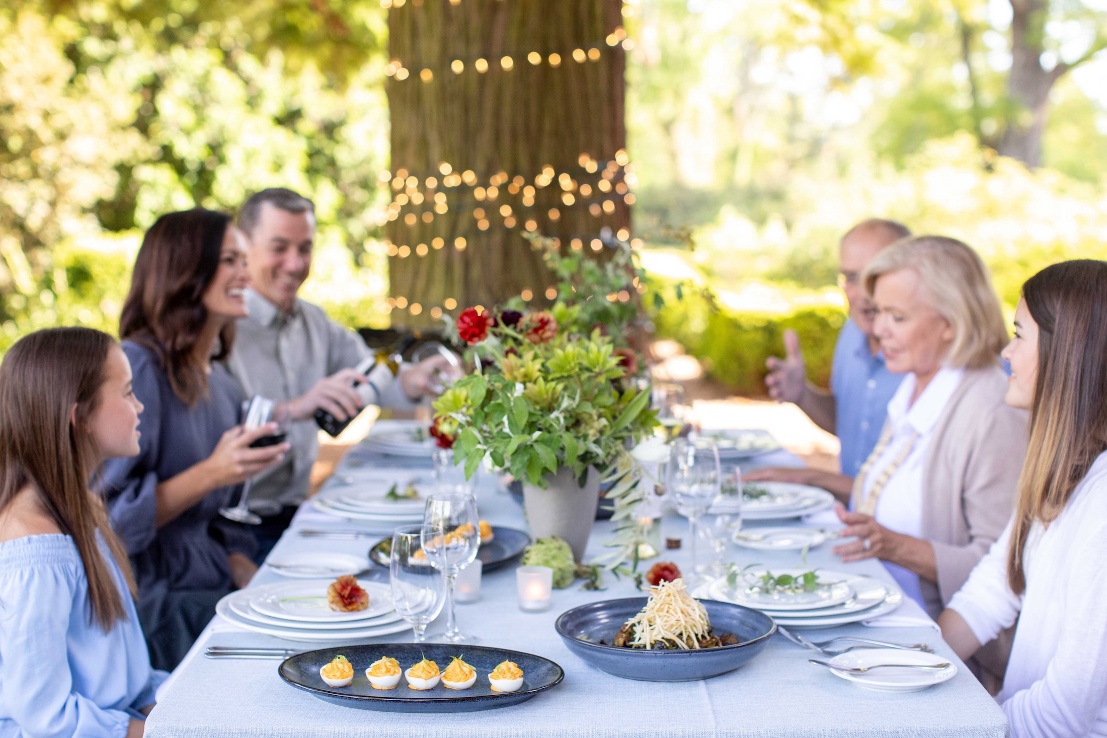 A family enjoys dinner at a table set up outdoors.