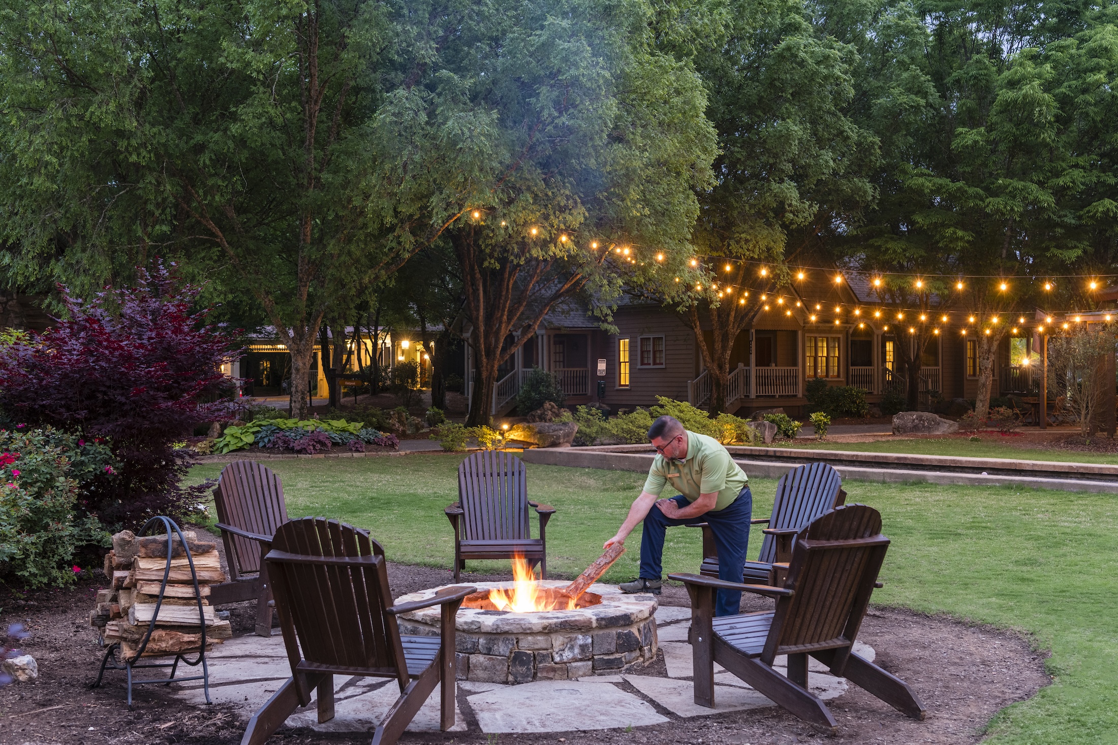 A man puts a log on a fire in a fire pit at Barnsley Resort.