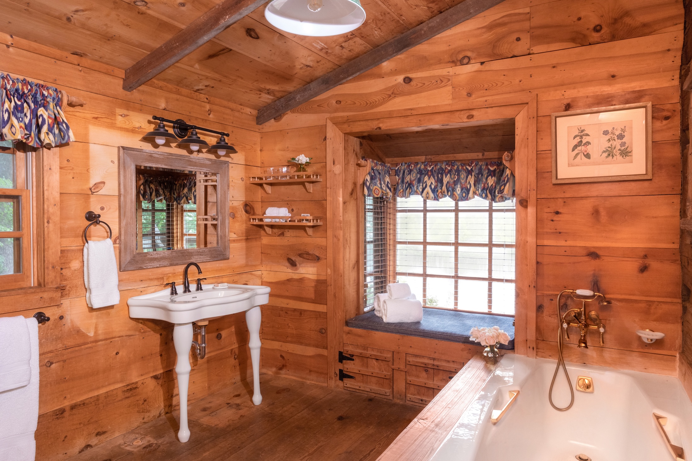 The primary bathroom rustic wooden walls and gold finishes in Fugger Cabin at Barnsley Resort.