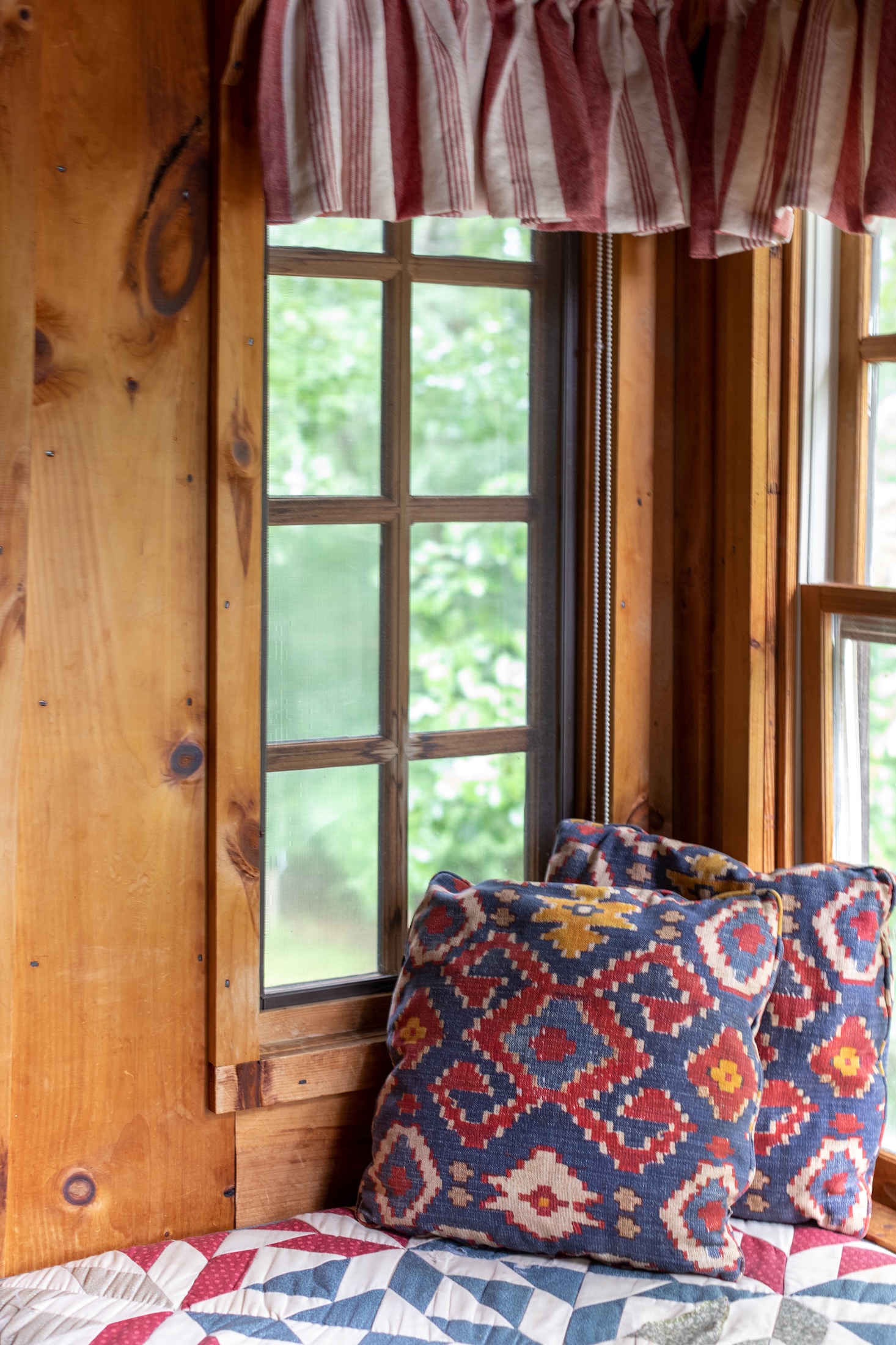 A window seat with plush pillows and quilt in Fugger Cabin at Barnsley Resort.