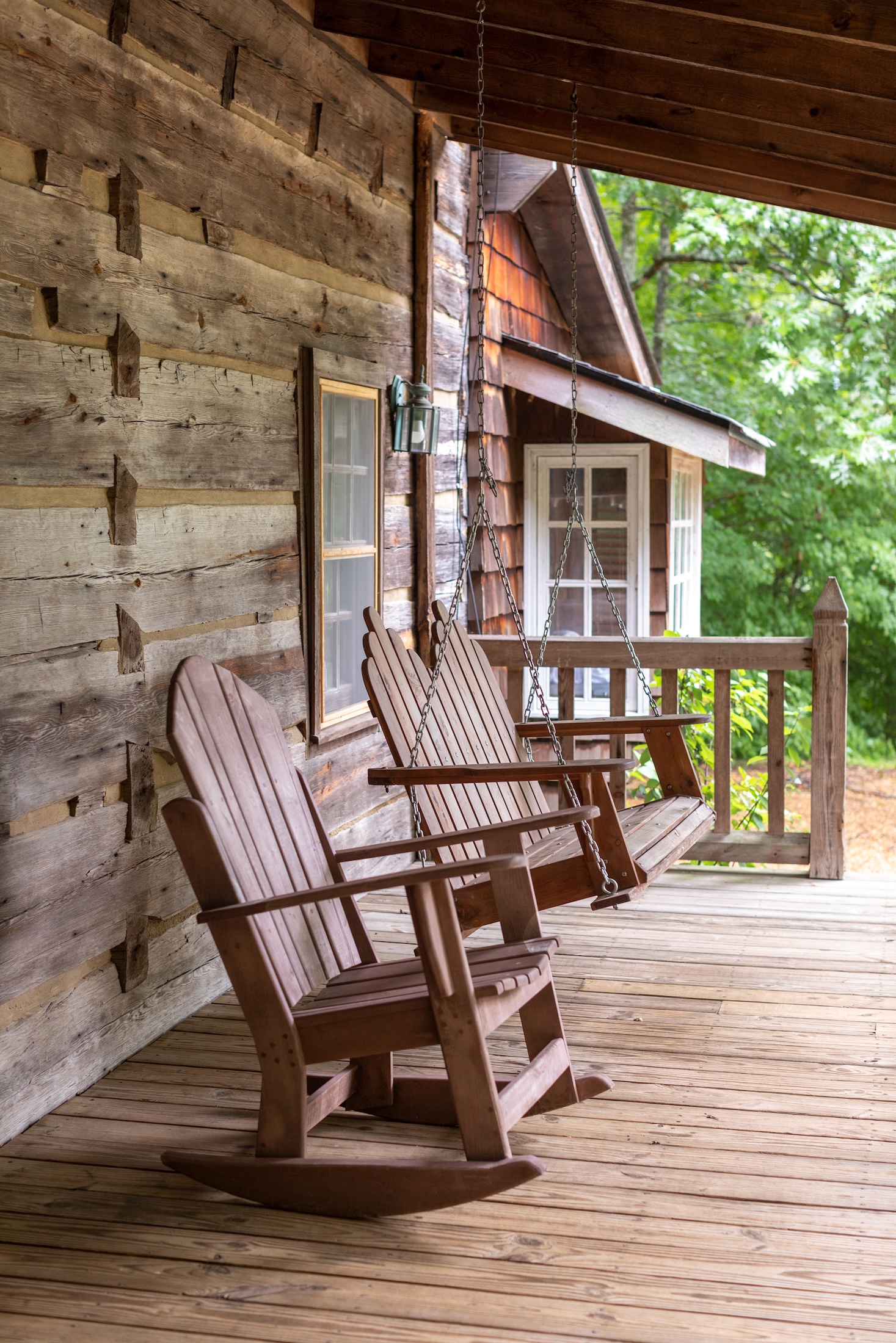 A wooden rocking chair and hanging wooden swing on the Fugger Cabin porch at Barnsley Resort.