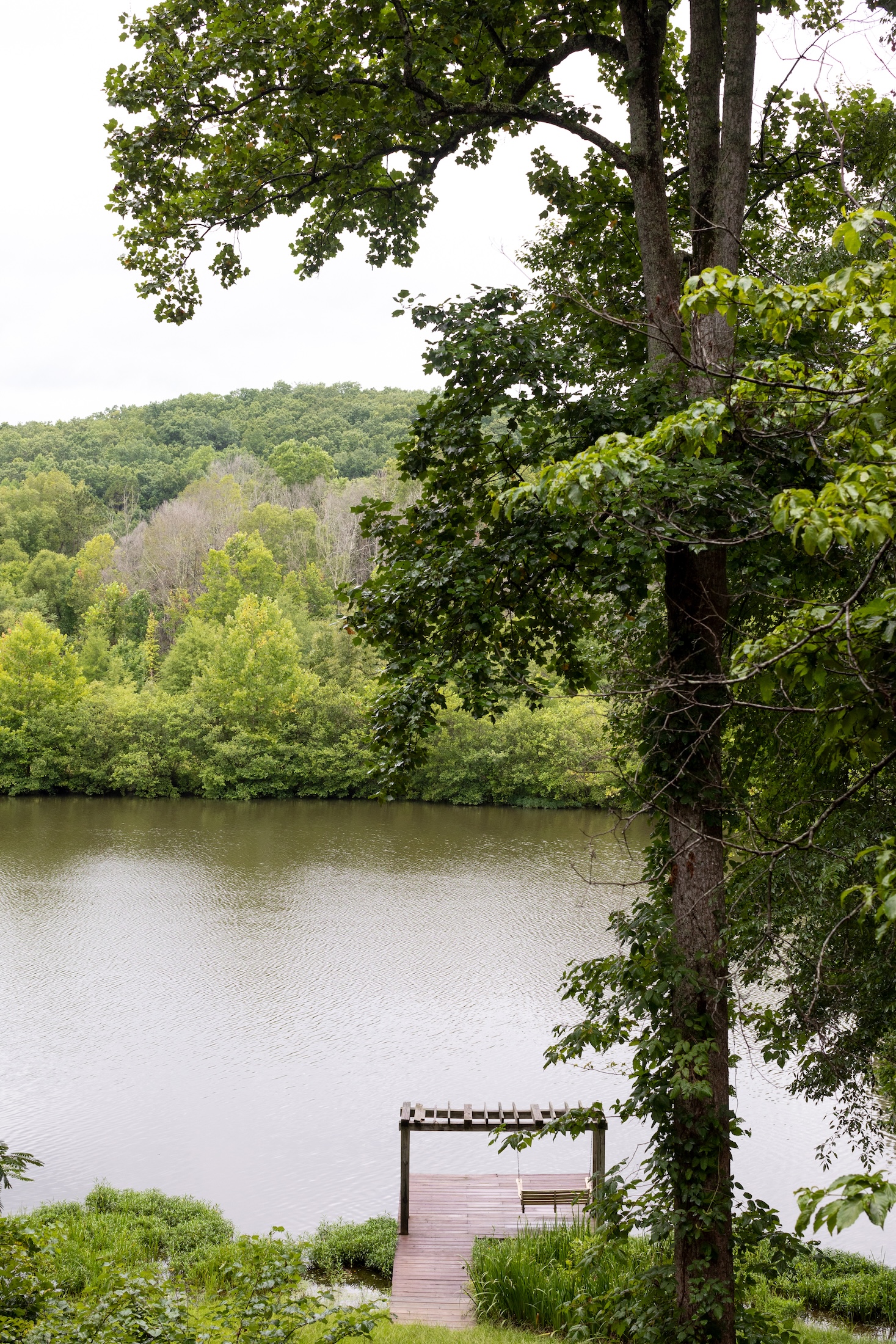 A view of the lake and private dock surrounded by lush, green trees at Fugger Cabin.