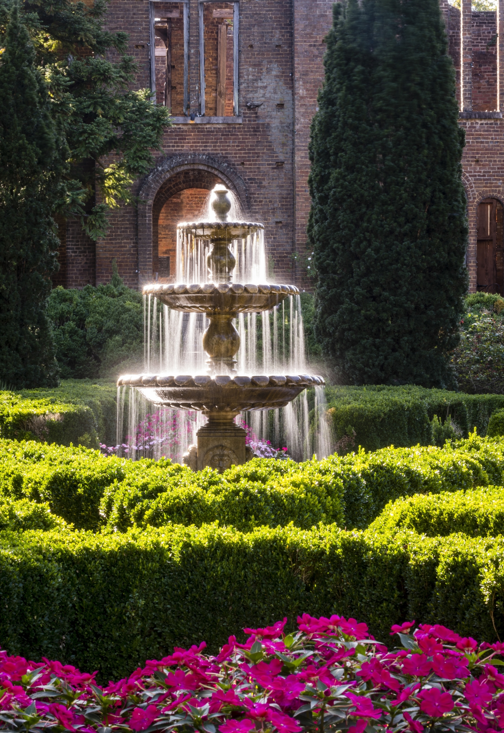 A fountain in lush gardens on a sunny day.