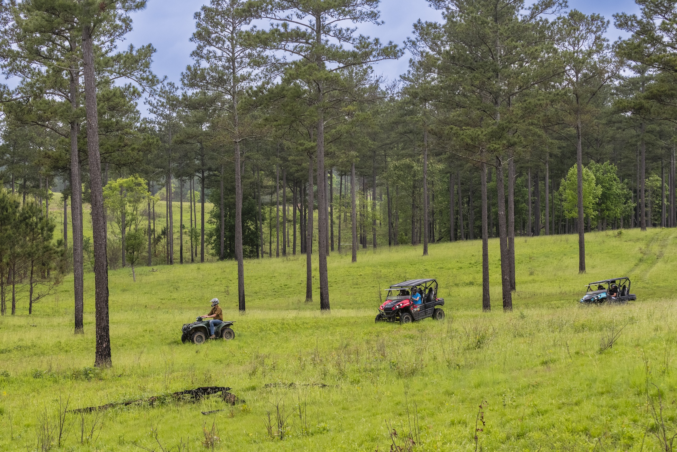 Three UTVs driving through a field at Barnsley Resort.