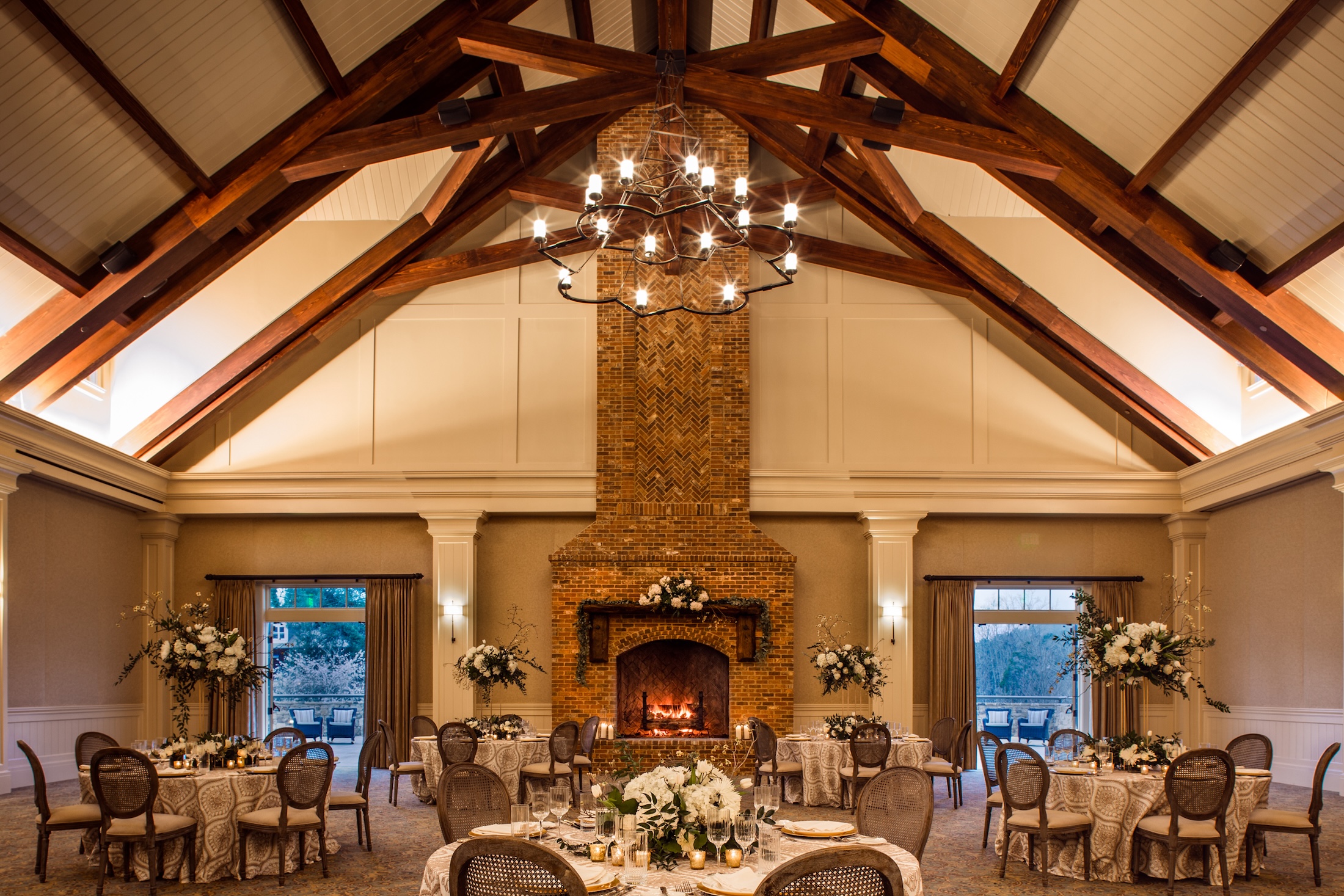 A cozy meeting room with vaulted ceilings, fire place and multiple tables set for an event in Georgian Hall in the evening.