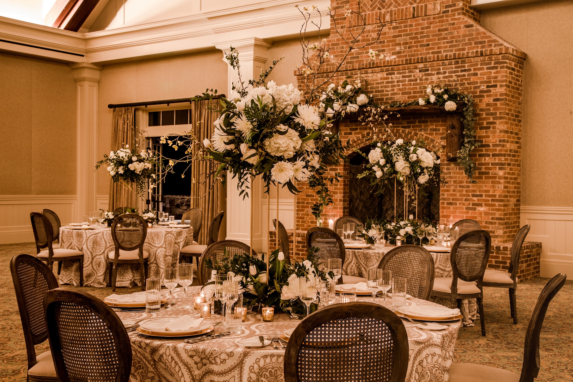 A cozy meeting room with vaulted ceilings, fire place and multiple tables set for an event in Georgian Hall.