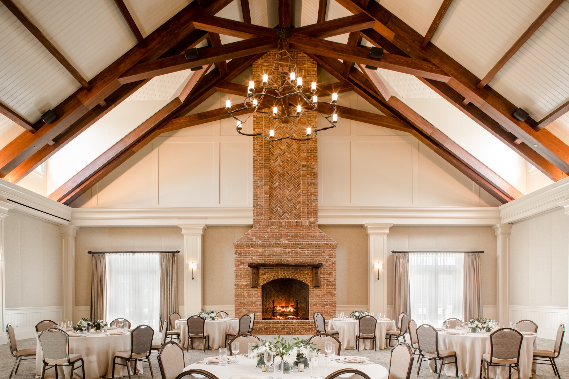 A cozy meeting room with vaulted ceilings, fire place and multiple tables set for an event in Georgian Hall.