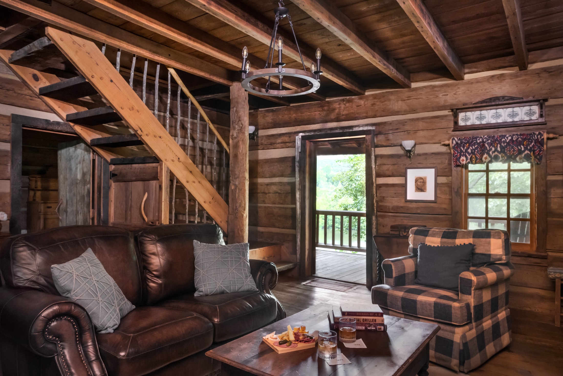 A cozy living room with leather couch and plush arm chair in the wooden Fugger Cabin at Barnsley Resort.