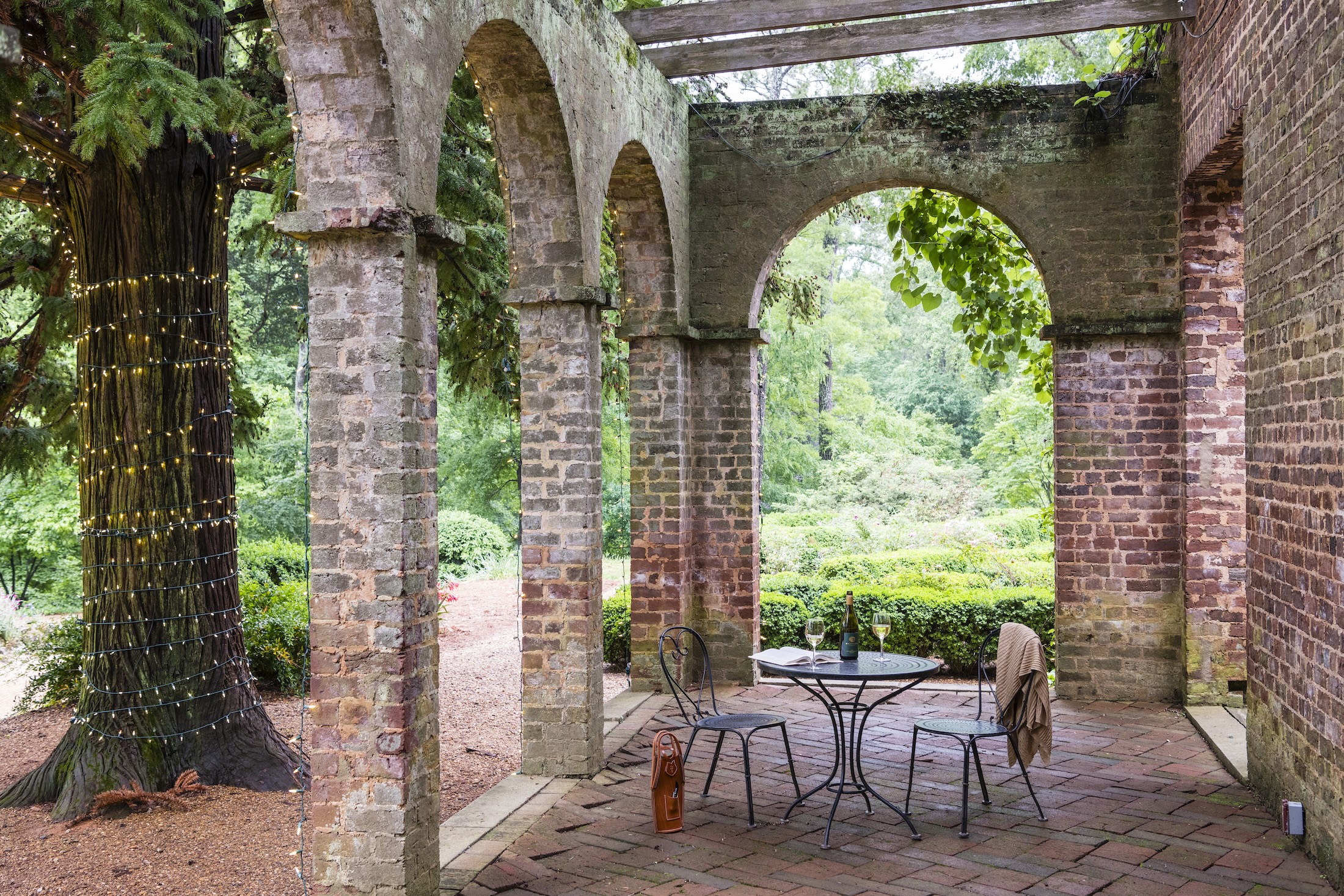 An iron patio table with two chairs, a blanket and champagne is set up in the ruins at Barnsley Resort.