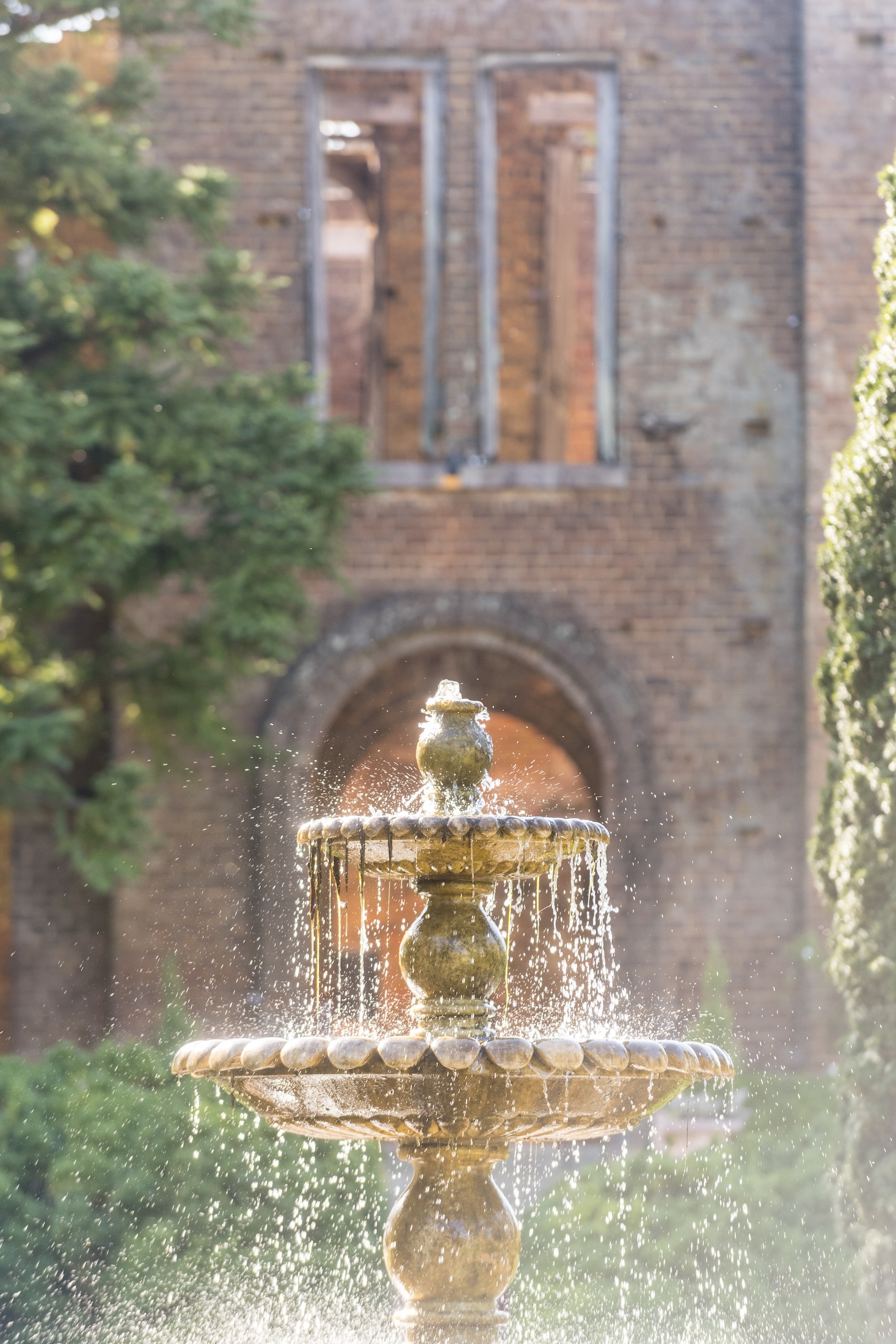 A fountain sparkling in the sun with the Manor House Ruins in the background.