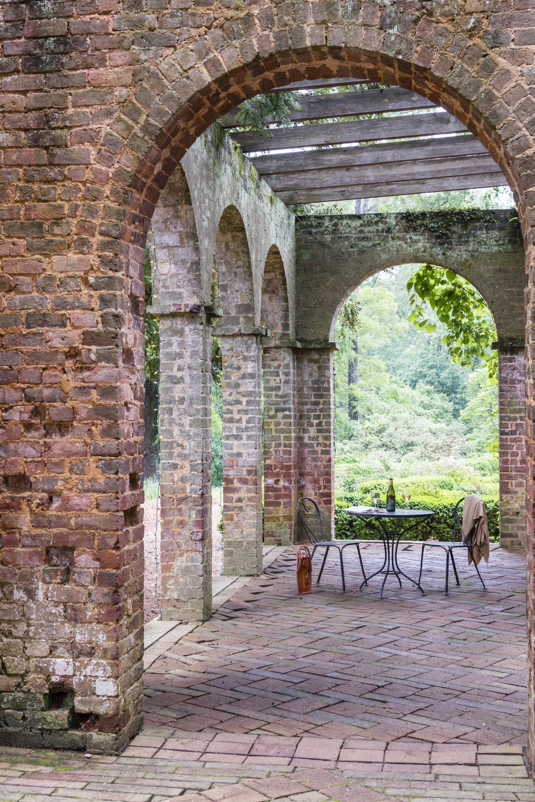 An iron patio table with two chairs, a blanket and champagne is set up in the ruins at Barnsley Resort.