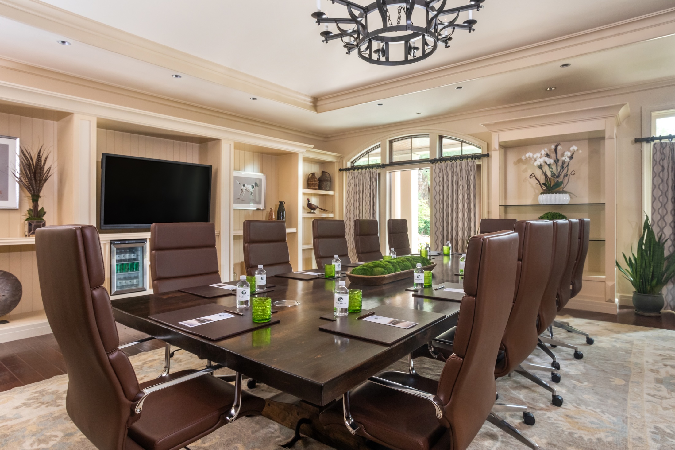 The interior of a board room with a wooden table and leather seats at Barnsley Resort.