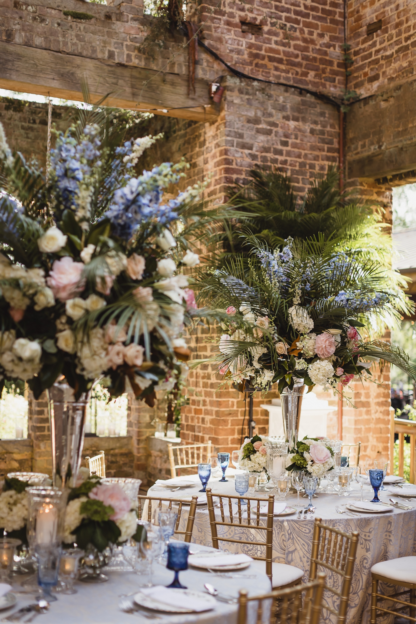 An outdoor wedding venue with tables set with floral and candle placements.