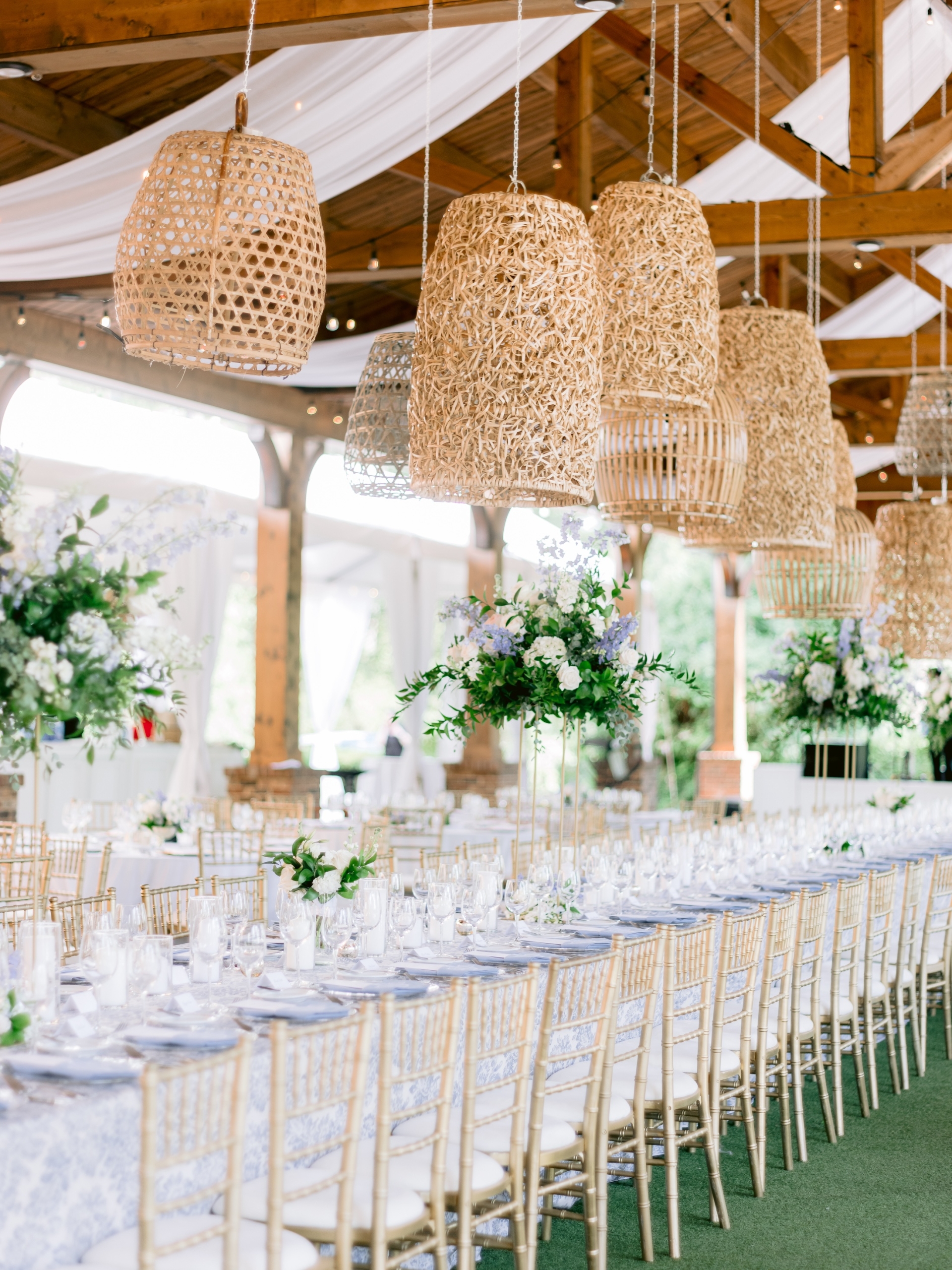 An outdoor wedding venue with long banquet tables set with floral and candle placements.