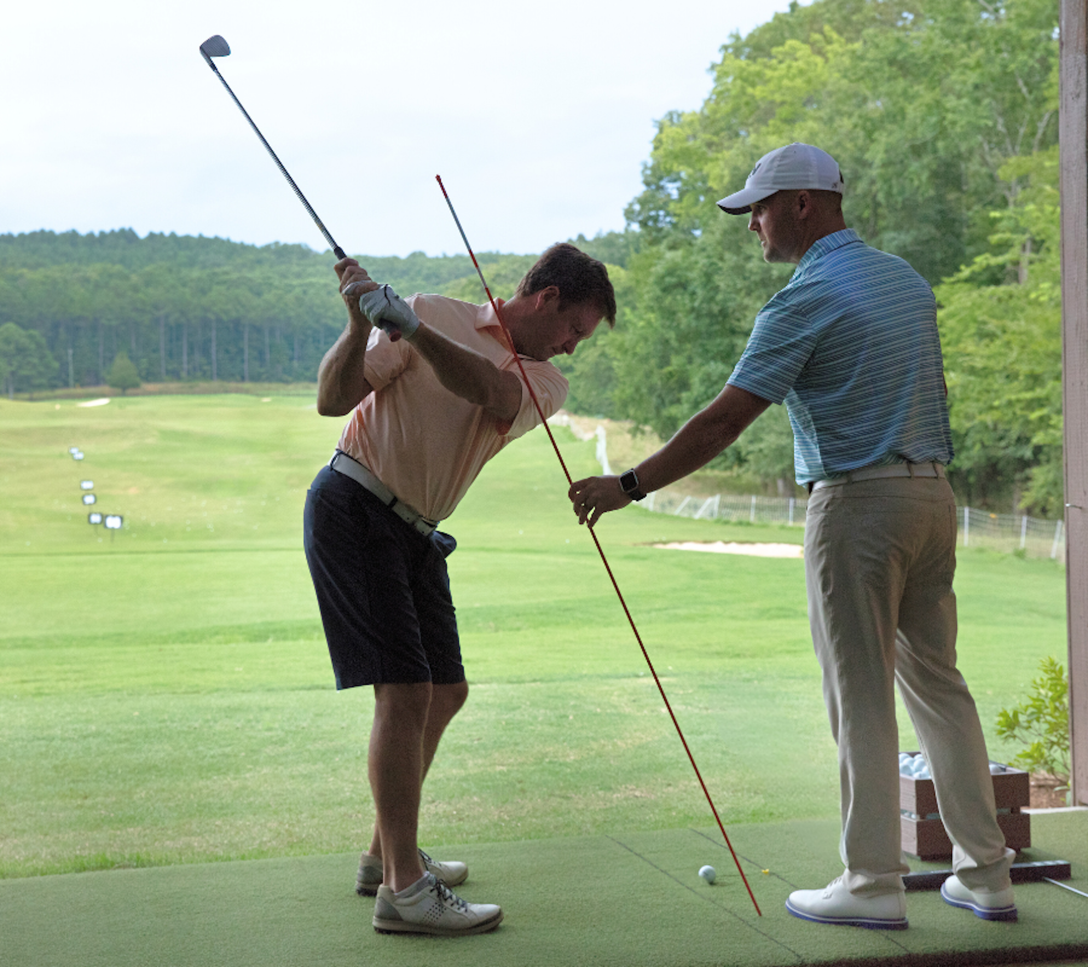 A golf instructor instructing a student on their swing at the Golf Performance Center at Barnsley Resort.