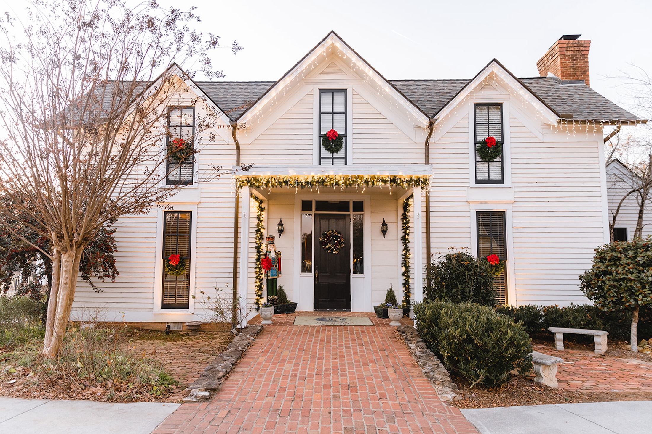 The exterior of Rice House decorated with white Christmas lights and wreaths.