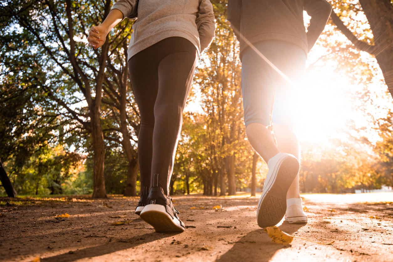 Close up of two people jogging in autumn day at the park.