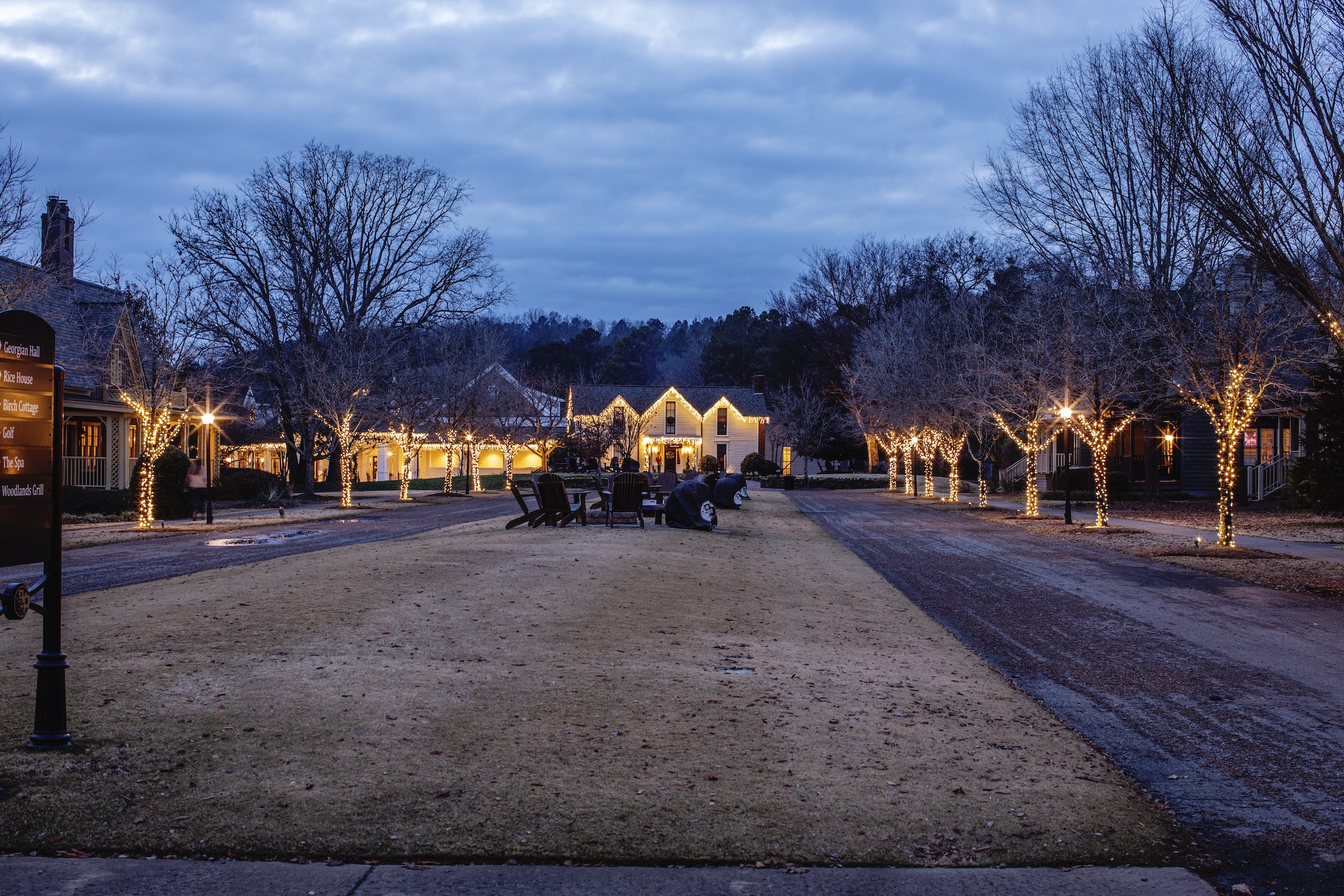 The Barnsley Resort Village at dusk, trees and buildings illuminated in white holiday lights.