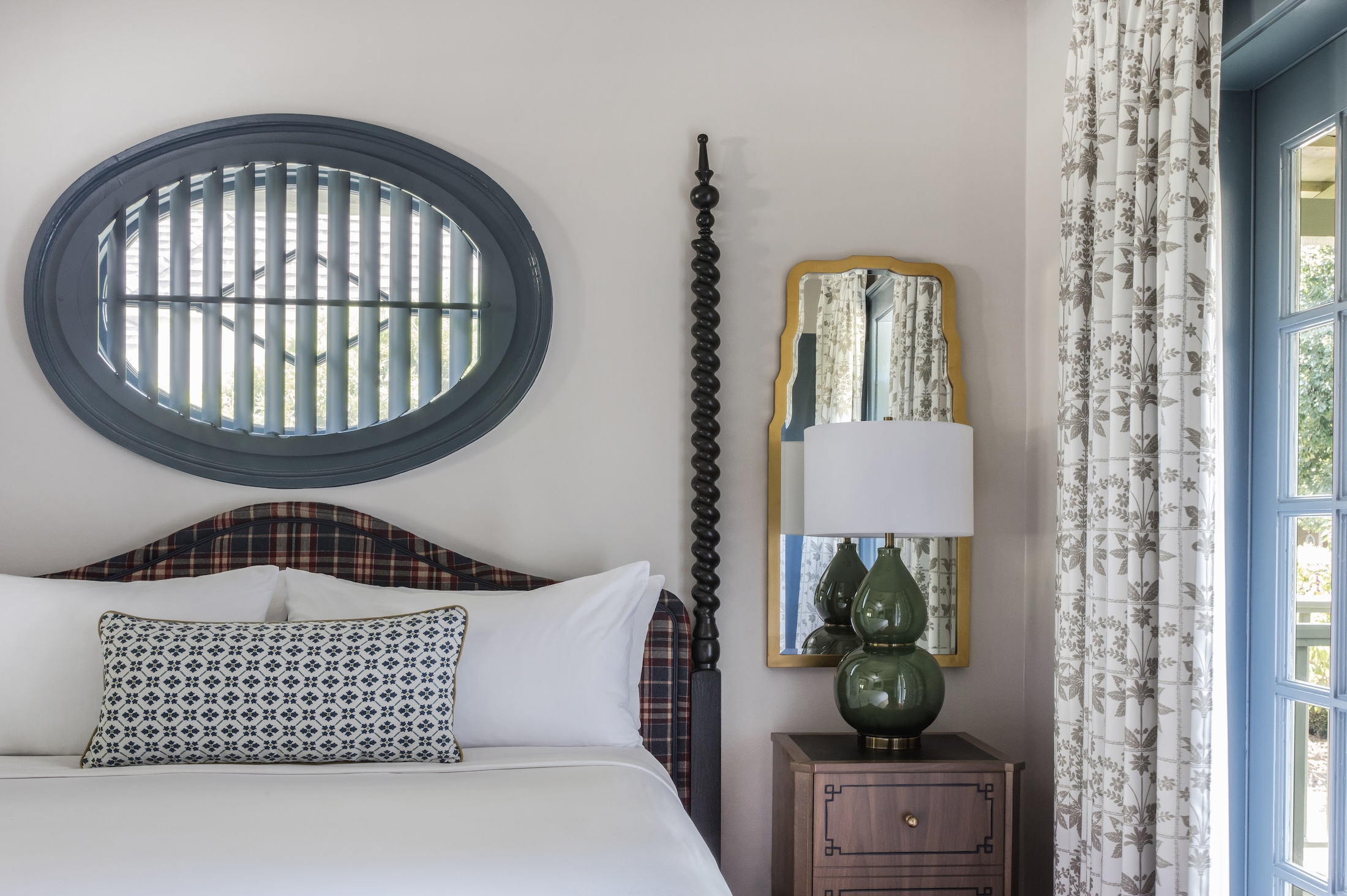 Cottage bedroom at Barnsley Resort, queen bed with country style window above, beside is a side table with a large green lamp