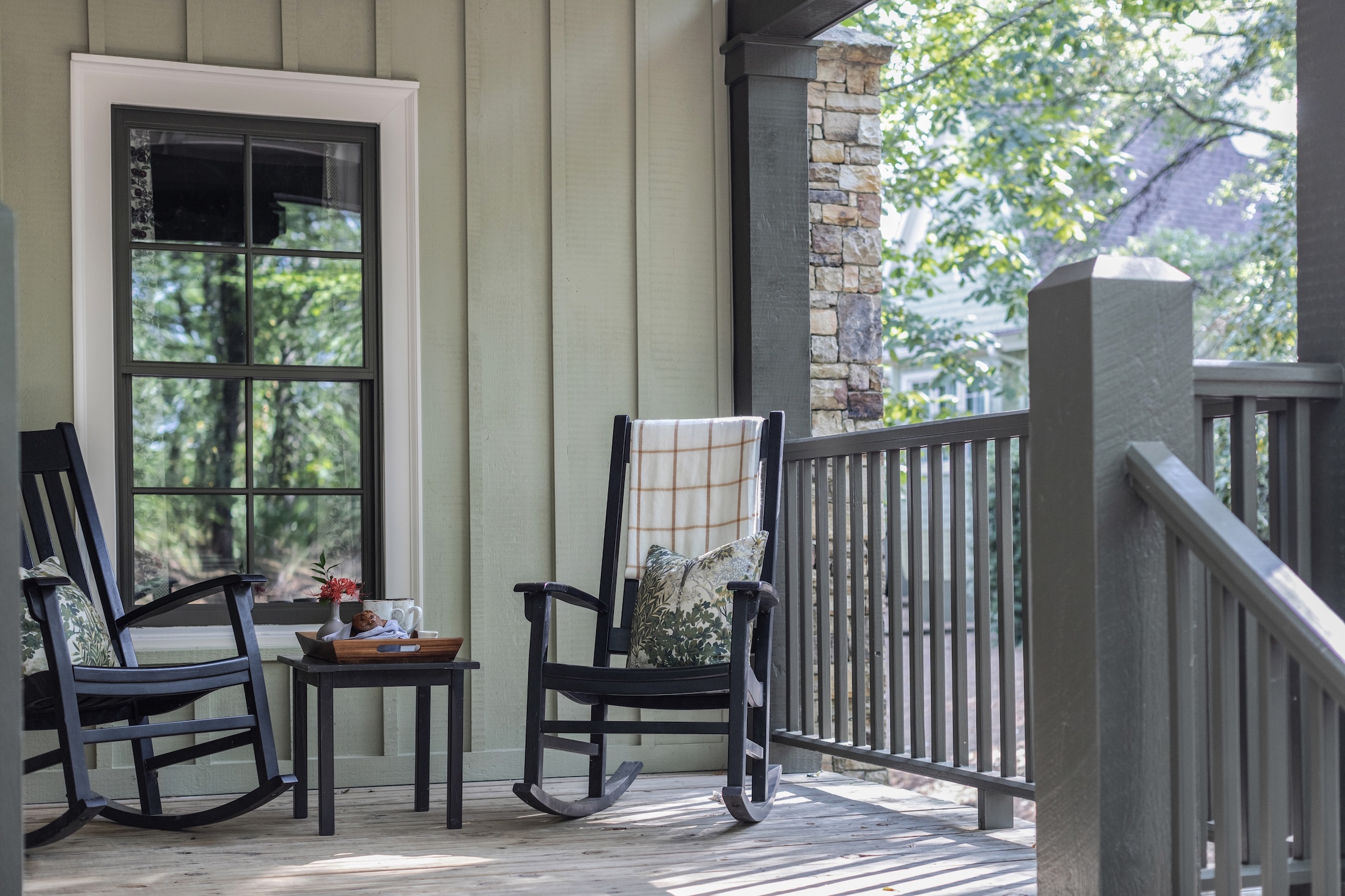 Julia Cottages at Barnsley Resort, long view of outdoor porch with two rocking chairs with pillows and sharing in the middle a breakfast with coffee and muffins