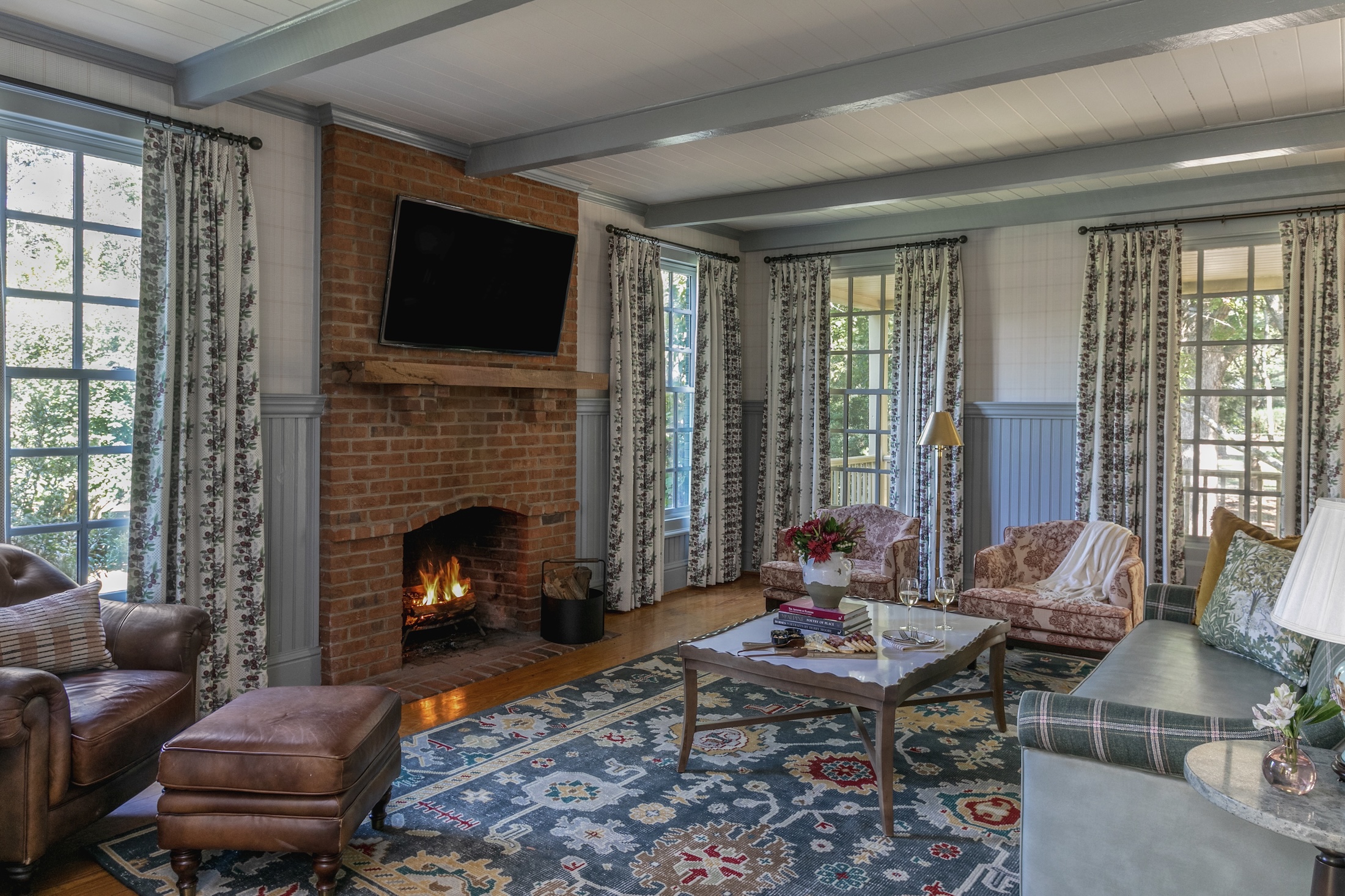 The living room of Wheaton Cottage, with plush furniture in soft colors. A fire is lit in the fireplace.