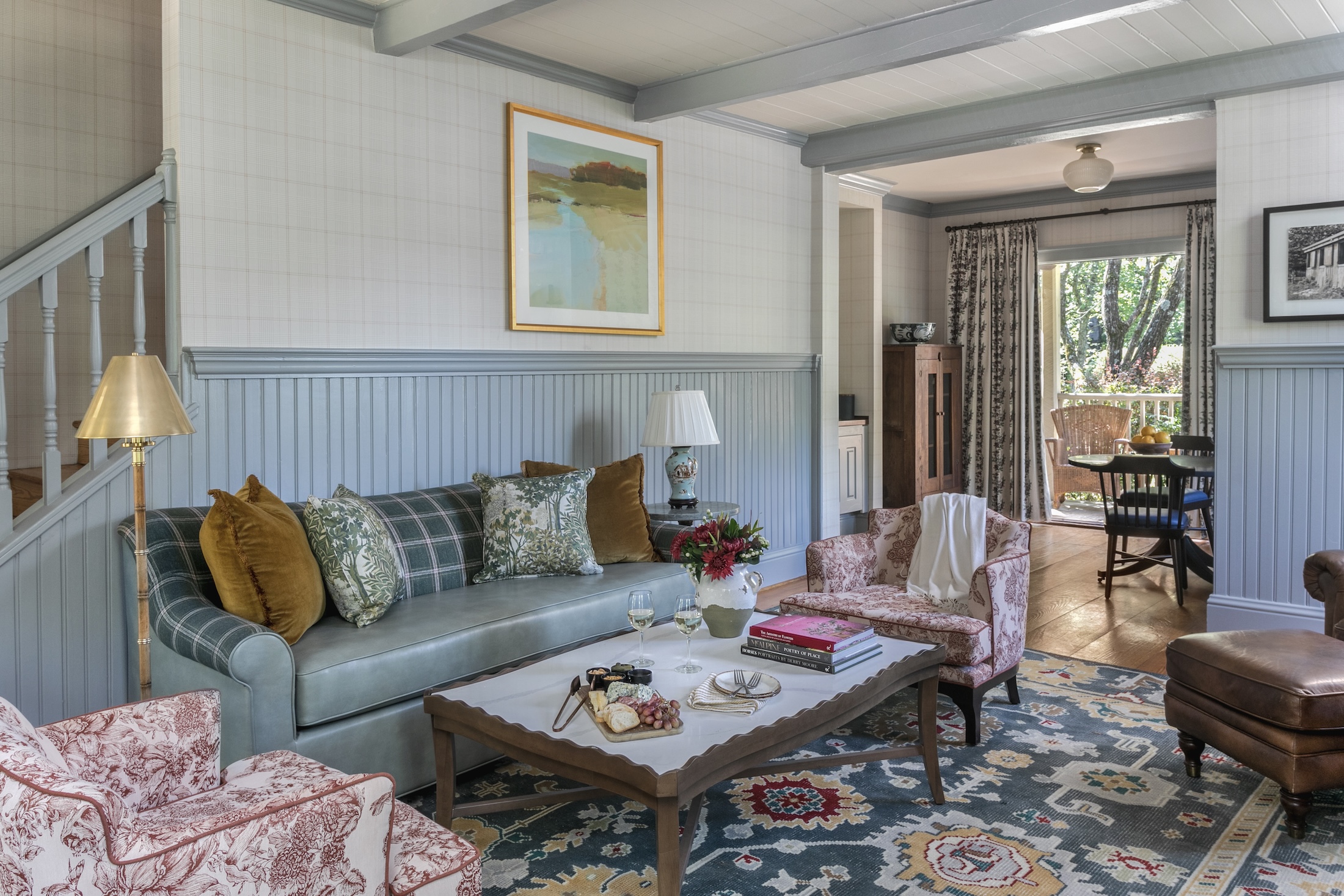 The living room of Wheaton Cottage, with plush furniture in soft colors. A furnished, sunny patio can be seen in the background.