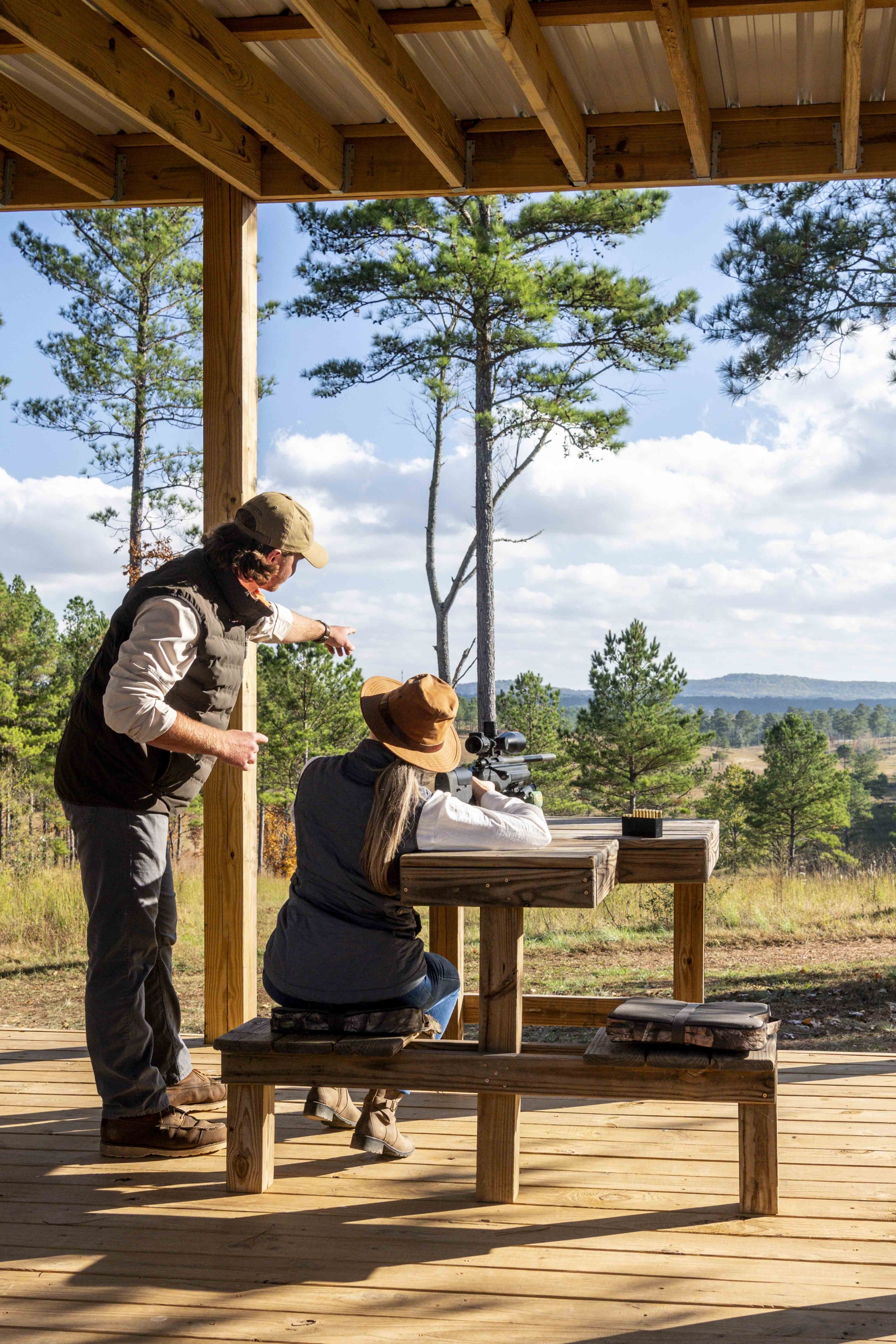 A man points out at a target in the distance for the woman to aim her gun at at Beretta Shooting Grounds.