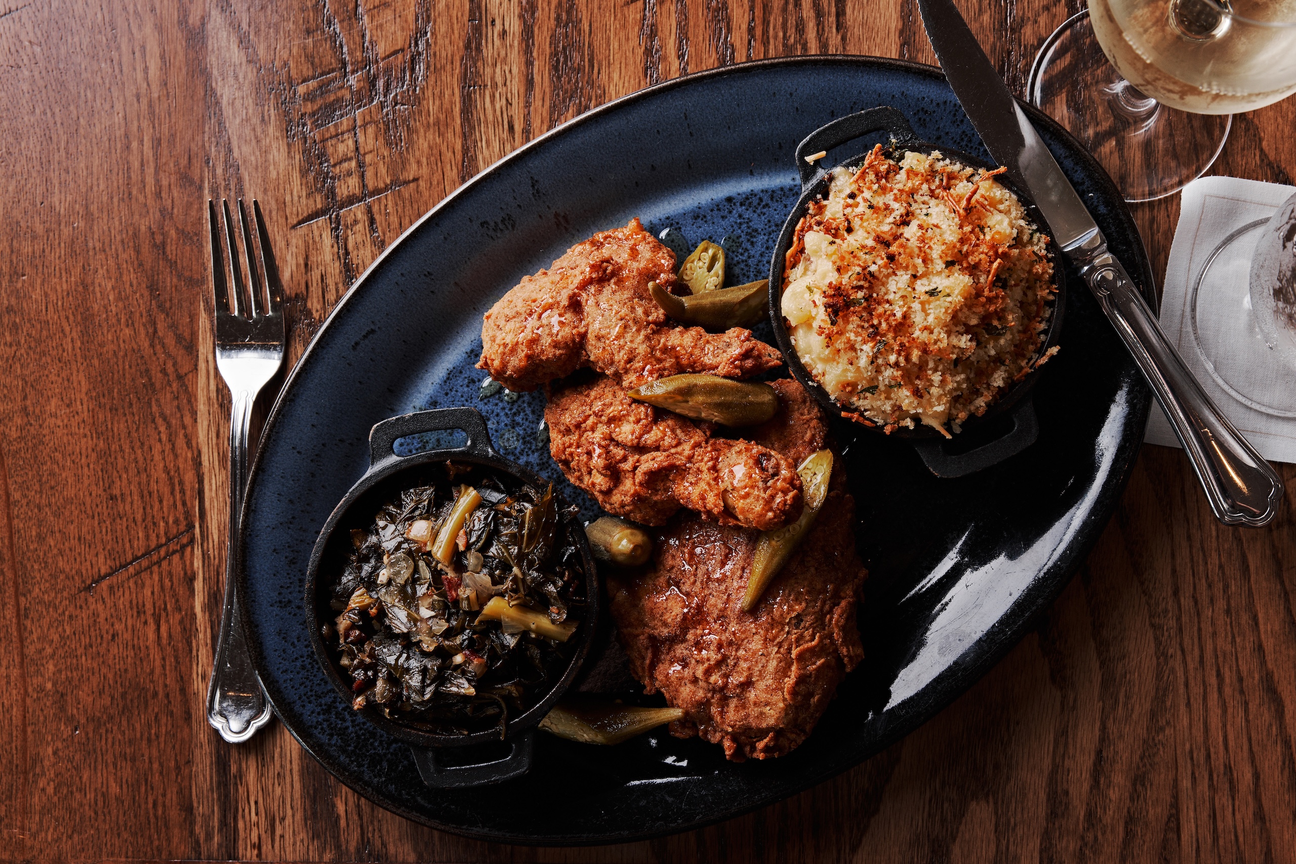 Fried chicken and mac-and-cheese with collard greens and a glass of white wine.