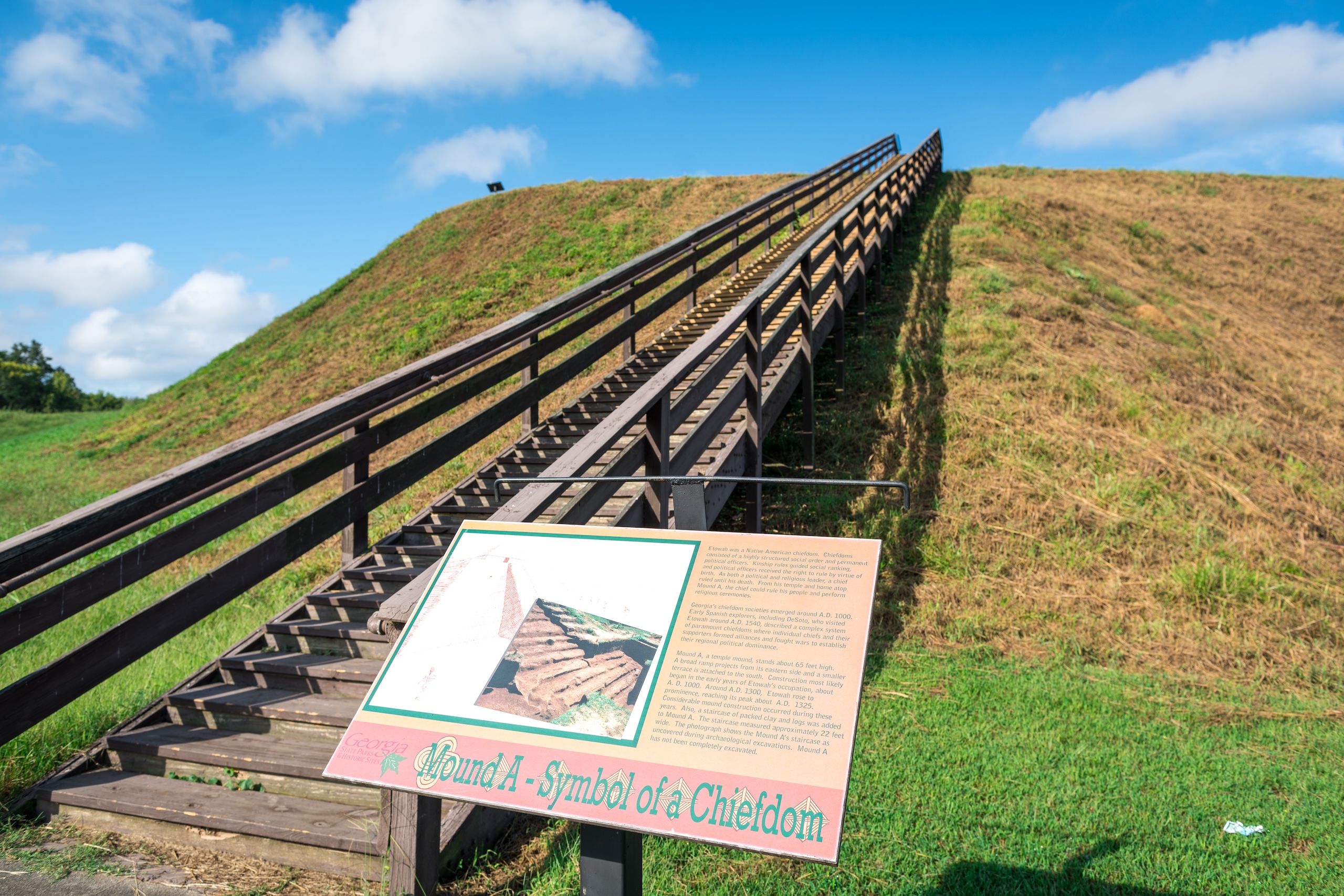 The bottom of the staircase leading up Etowah Indian Mounds, an information sign in front.